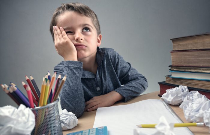 Thinking child bored, frustrated and fed up doing his homework